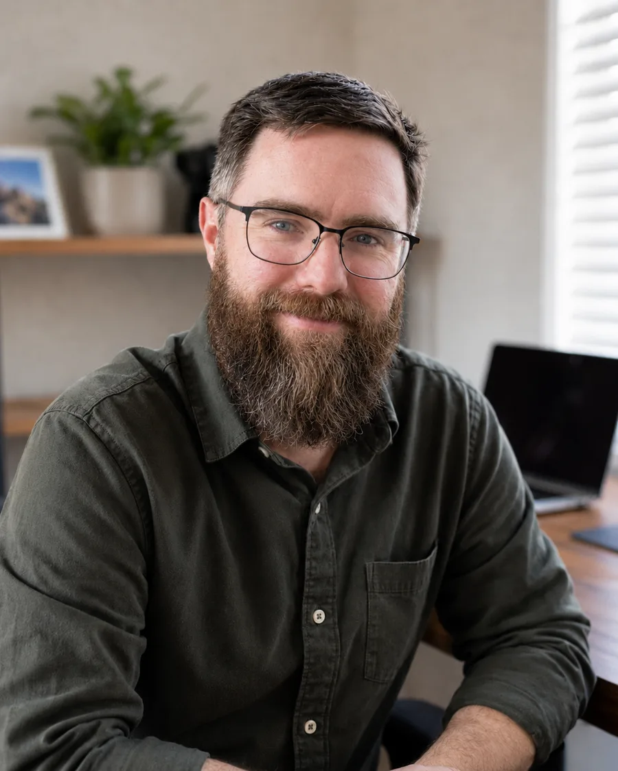John, a bearded man in glasses, seated at his desk.